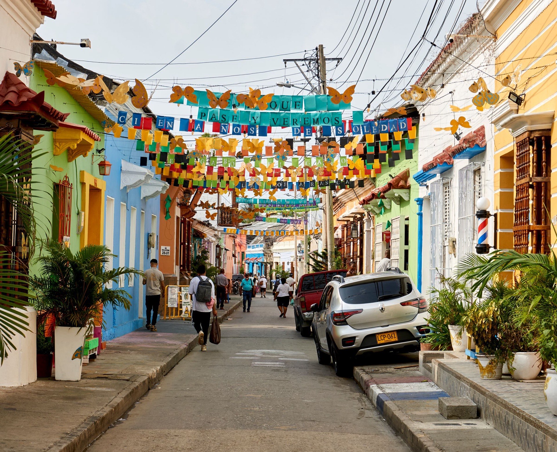 A street in Getsemaní, Cartagena, strung with rows of colorful paper flags above brightly painted houses, with people walking below